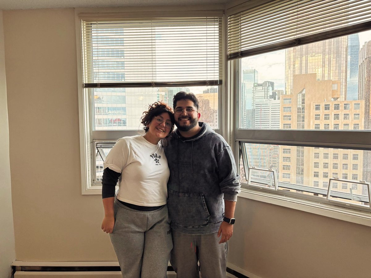 Pareja posando frente a grandes ventanales en su nuevo hogar